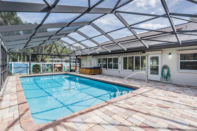 view of swimming pool with glass enclosure and a patio