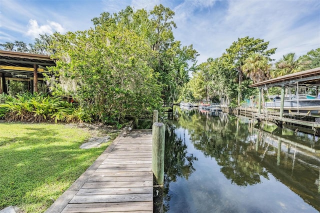 view of dock with a lawn and a water view