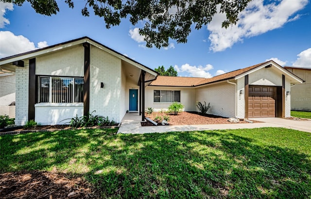 ranch-style house with a garage, a front lawn, concrete driveway, and brick siding