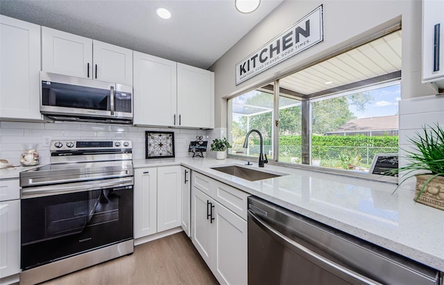 kitchen featuring a healthy amount of sunlight, stainless steel appliances, sink, and white cabinets