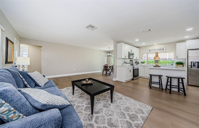 living room featuring a textured ceiling, a notable chandelier, and hardwood / wood-style flooring