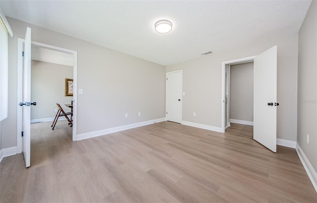 unfurnished bedroom featuring a textured ceiling and light hardwood / wood-style flooring