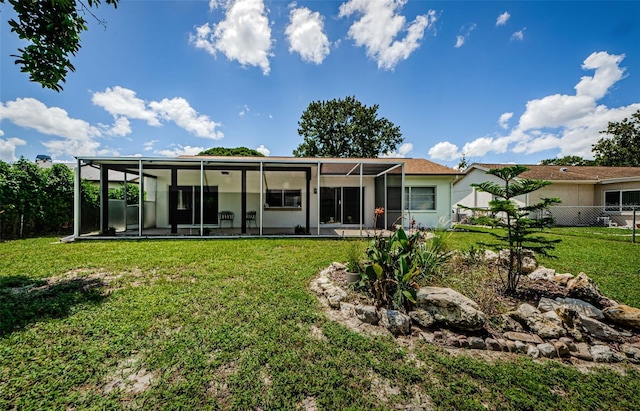 rear view of house with a sunroom and a yard