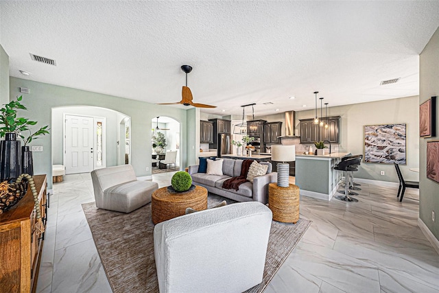 living room featuring ceiling fan and a textured ceiling