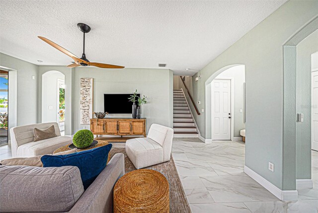 living room with a textured ceiling and ceiling fan