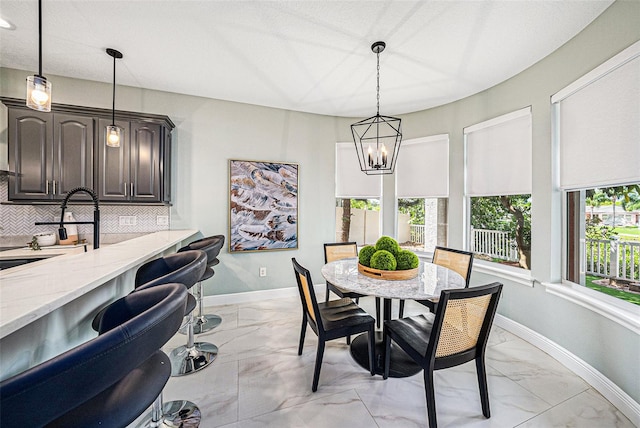 dining room with a textured ceiling, sink, and a notable chandelier