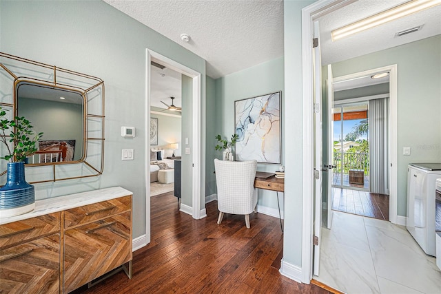 hallway featuring a textured ceiling, hardwood / wood-style floors, and washer and dryer