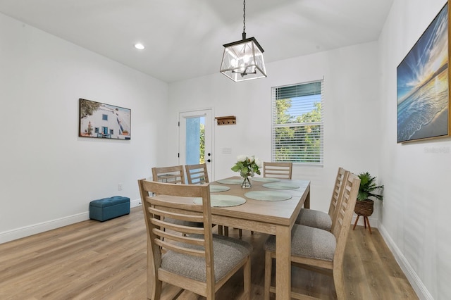 dining space with light hardwood / wood-style flooring and a chandelier