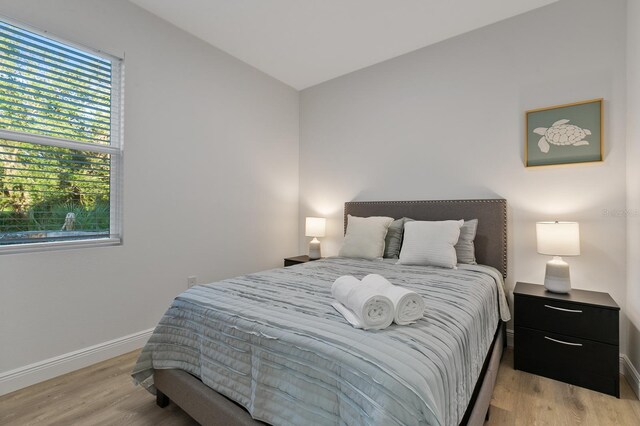 bedroom with multiple windows, lofted ceiling, and light hardwood / wood-style flooring