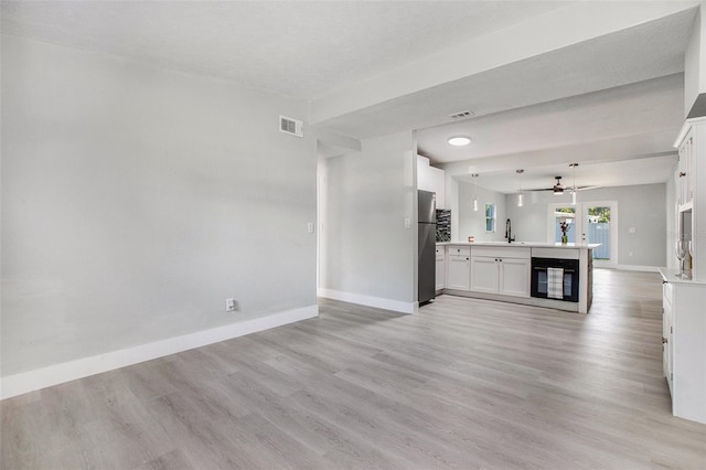 unfurnished living room with light hardwood / wood-style flooring, ceiling fan, and sink