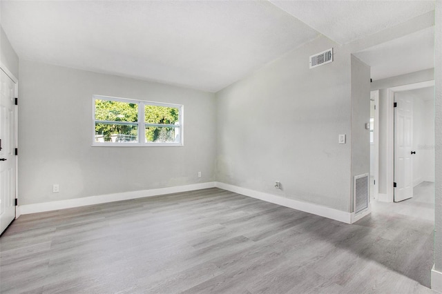 spare room featuring vaulted ceiling and light hardwood / wood-style flooring