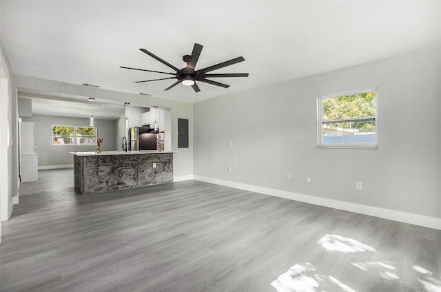 unfurnished living room featuring hardwood / wood-style flooring, a wealth of natural light, electric panel, and ceiling fan