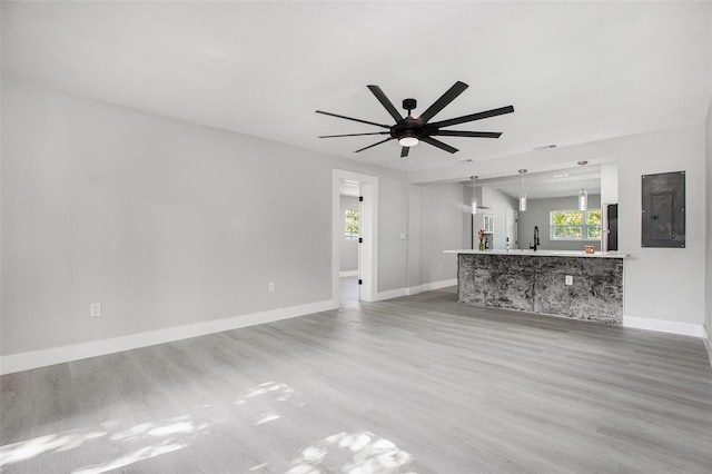 unfurnished living room with ceiling fan, sink, and light wood-type flooring