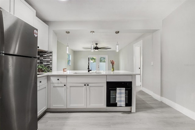 kitchen featuring stainless steel refrigerator, sink, light wood-type flooring, and tasteful backsplash