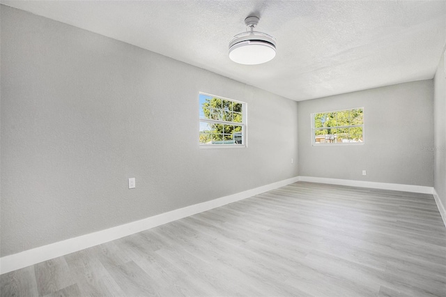 unfurnished room with a textured ceiling and light hardwood / wood-style floors