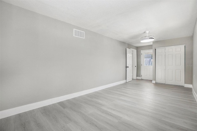 spare room with light hardwood / wood-style floors and a textured ceiling