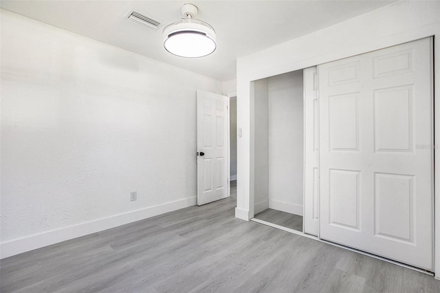 unfurnished bedroom featuring light wood-type flooring and a closet