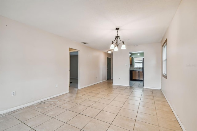 unfurnished room with an inviting chandelier, sink, and light tile patterned flooring