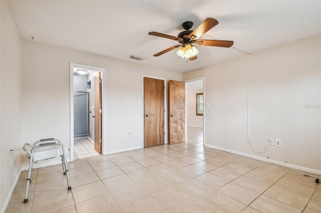 unfurnished bedroom featuring ceiling fan, connected bathroom, and light tile patterned flooring