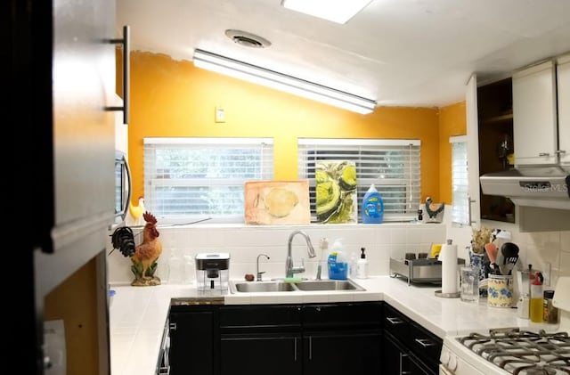 kitchen featuring lofted ceiling, decorative backsplash, white stove, and sink