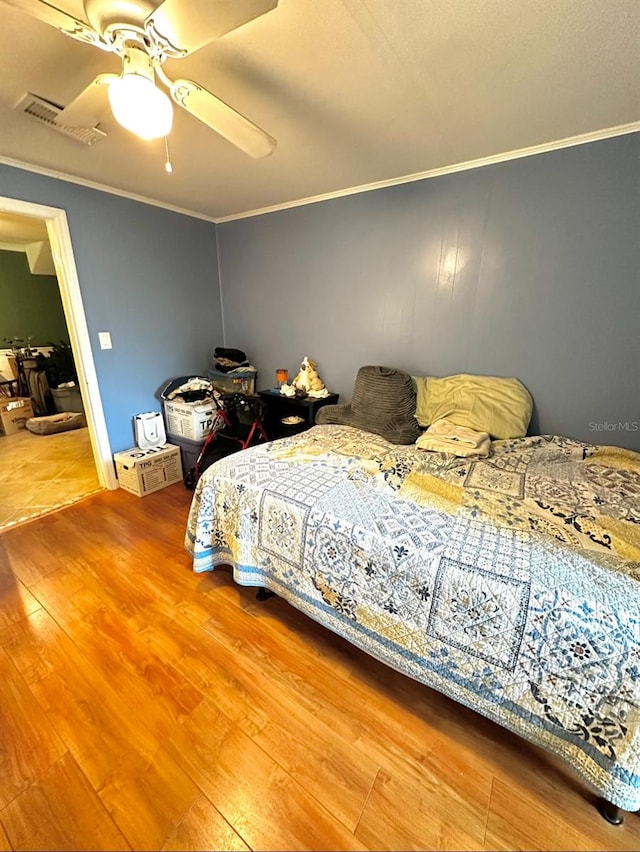 bedroom featuring crown molding, hardwood / wood-style floors, and ceiling fan