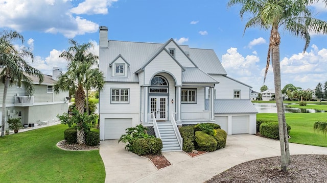 view of front facade featuring a garage, a water view, and a front lawn