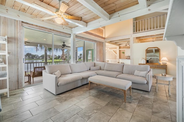 living room with a towering ceiling, beam ceiling, ceiling fan, and wood ceiling