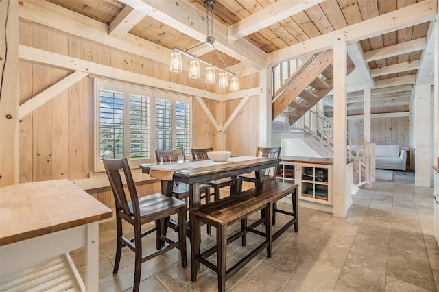 dining room with beamed ceiling, wooden walls, and wooden ceiling