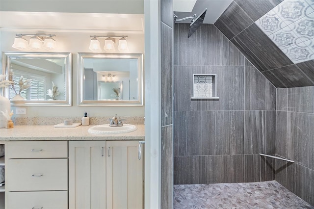 bathroom featuring vanity, tiled shower, and vaulted ceiling