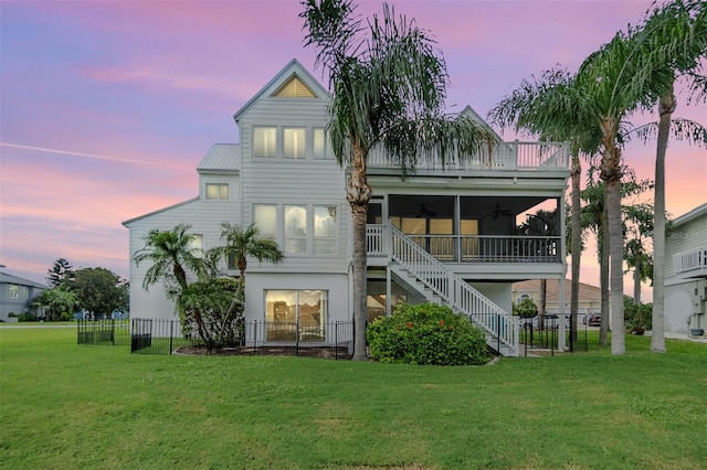 back house at dusk featuring ceiling fan and a yard