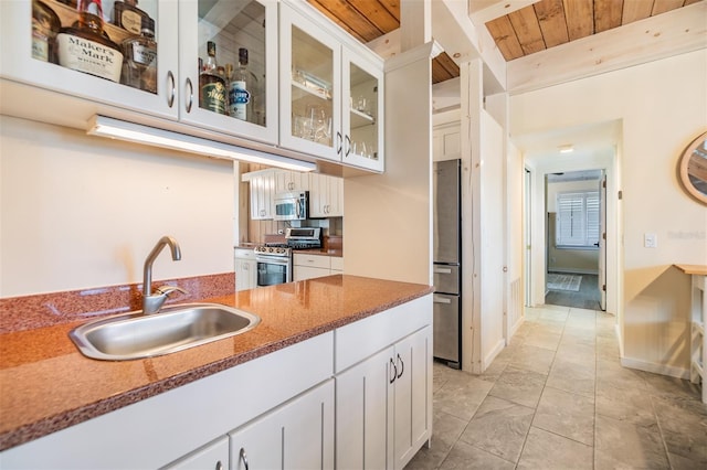 kitchen featuring stainless steel appliances, wooden ceiling, sink, beam ceiling, and white cabinets