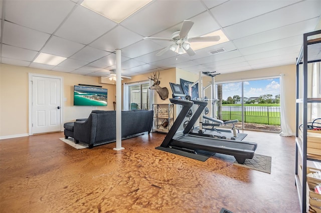 workout area with concrete flooring, ceiling fan, and a paneled ceiling