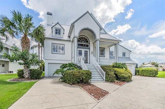 2118 Harbour Watch Dr, Tarpon Springs, FL 34689 - view of front of property featuring stairs, french doors, an attached garage, metal roof, and concrete driveway