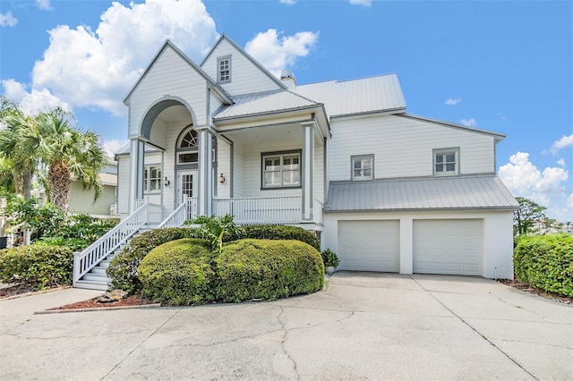 2118 Harbour Watch Dr, Tarpon Springs, FL 34689 - view of front facade with metal roof, an attached garage, concrete driveway, covered porch, and stairway