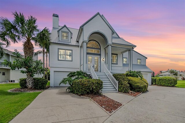 2118 Harbour Watch Dr, Tarpon Springs, FL 34689 - view of front facade featuring french doors, a garage, stairs, concrete driveway, and metal roof