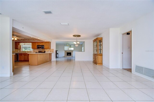 unfurnished living room featuring light tile patterned floors, a tile fireplace, and a chandelier