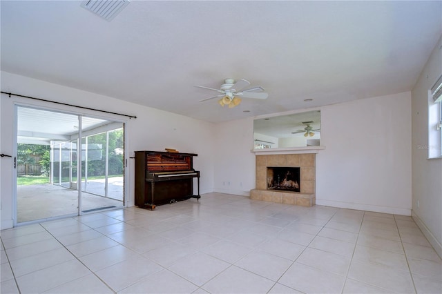 unfurnished living room with a tiled fireplace, light tile patterned floors, and ceiling fan