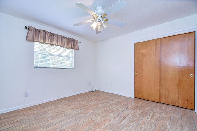 unfurnished bedroom with light hardwood / wood-style flooring, ceiling fan, and a closet