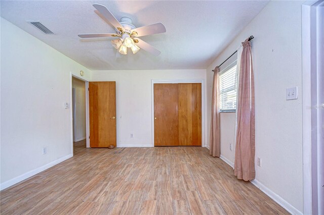 unfurnished bedroom featuring a textured ceiling, ceiling fan, a closet, and light hardwood / wood-style floors