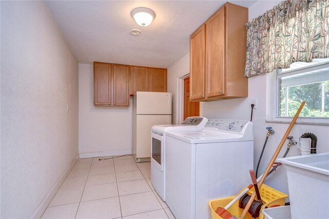 clothes washing area with cabinets, sink, washing machine and dryer, and light tile patterned flooring