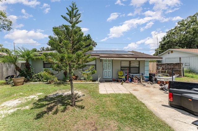 rear view of house with a lawn, a patio area, and solar panels