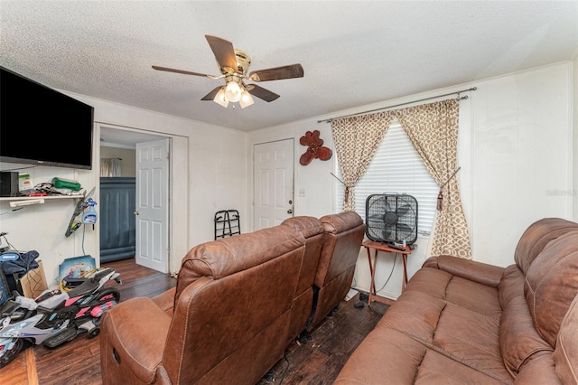 living room featuring dark wood-type flooring, ceiling fan, and a textured ceiling