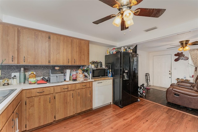 kitchen featuring dishwasher, tasteful backsplash, black fridge, ceiling fan, and light wood-type flooring