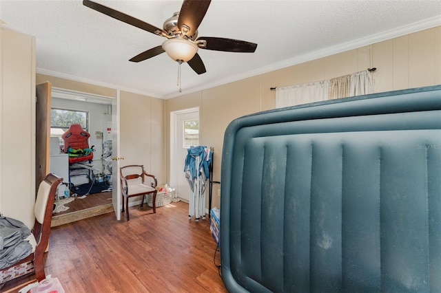 bedroom featuring a textured ceiling, dark wood-type flooring, ceiling fan, and ornamental molding