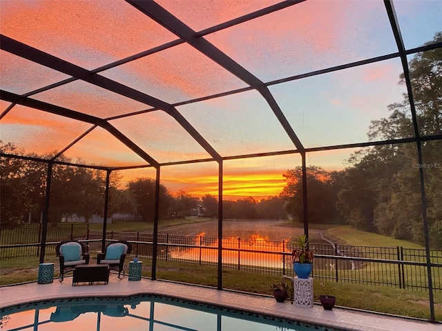 pool at dusk featuring a patio and glass enclosure