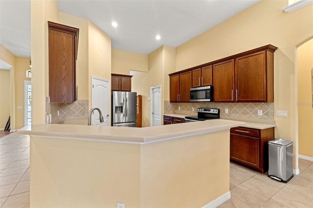 kitchen with sink, light tile patterned floors, tasteful backsplash, kitchen peninsula, and stainless steel appliances