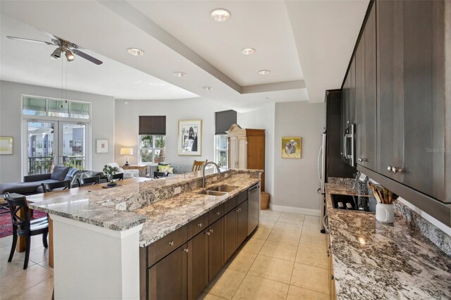 kitchen featuring light tile patterned flooring, stainless steel appliances, a sink, open floor plan, and a large island