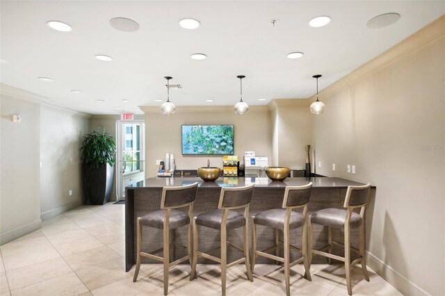 kitchen with dark countertops, crown molding, a peninsula, and a kitchen bar