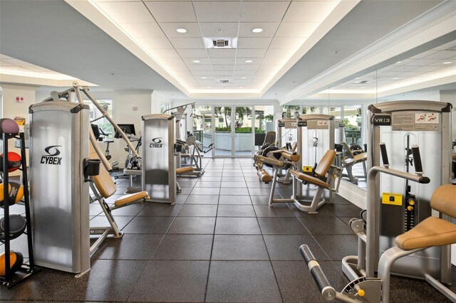 exercise room with a drop ceiling, a raised ceiling, visible vents, and recessed lighting