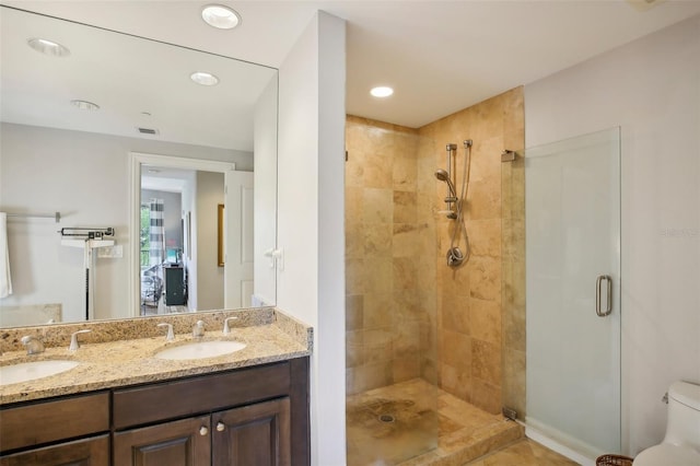 bathroom with double vanity, a sink, toilet, and a shower stall